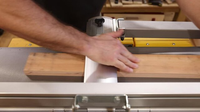 Carpenter planing wooden plank with surface planer in workshop