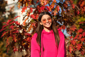 Girl in autumn style outdoor. Fall style fashion. Autumn leaves and happy young girl in forest. The color and mood of autumn. Teenager girl in the autumn park. Fall concept. Falling leaves