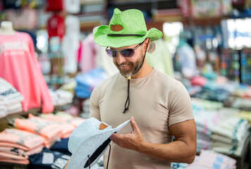 Stylish man in boutique. Mature man choosing hat. Male accessories store. Trendy fashion store. Handsome man trying on hat. Hat male fashion shop. Man shopping fashion hat. Custom-fit hats