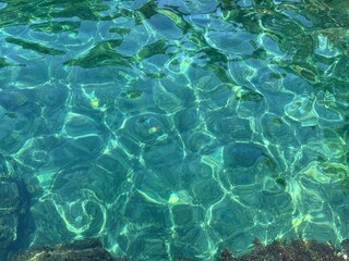 Beautiful crystal clear turquoise blue sea water surface with algae at the bottom.