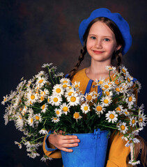 Close up portrait of young beautiful caucasian girl in blue beret and a bouquet of daisies posing on grey background. Beautiful curly hair.