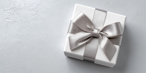 Gift box with satin ribbon on a light grey surface, elegant and simple anniversary concept, top view, minimal shadows.