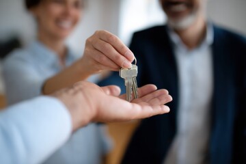 Happy real estate agent is handing over keys to new homeowner, symbolizing successful property transaction. joyful expressions reflect excitement and satisfaction in this moment
