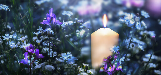 blooming flower meadow in an idyllic garden with white burning candlelight, floral design concept with copy space for gardening, holiday celebration, hope or mourning, greeting card
