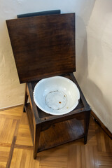 An old washbowl installed in a historical table with an open lid