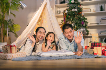 cheerful Asian father enjoys playful indoor camping with his sons, capturing fun memories as they take selfies and laugh together on the living room floor. Surrounded by cozy blankets and tents