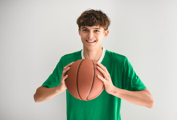 Basketball player holding ball on studio gray background