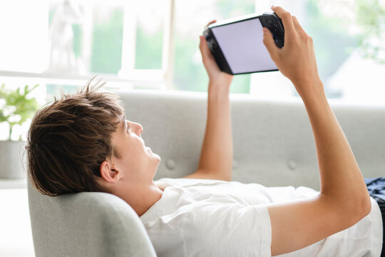 european teen play handheld console on sofa