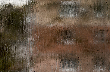 Wet glass window covered with tiny water droplets, creating blurry view through condensation....