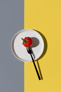Tomato balanced on a fork against vibrant colors