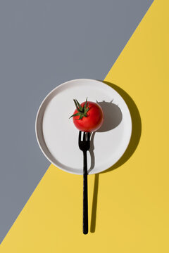 Tomato on a fork on a white plate with colorful background