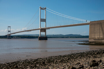 The old M48 Severn bridge from England to Wales.  Mid with stony shore in foreground