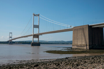 Fototapeta premium The old M48 Severn bridge from England to Wales. Mid with stony shore in foreground