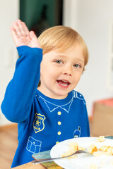 A child wearing a blue shirt is sitting at a table and eating enthusiastically. The moment captures a sense of appetite and the carefree nature of childhood. Diet for kids, homemade food