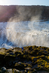 Majestic Dettifoss waterfall cascading in Iceland with visitors enjoying the view at sunset