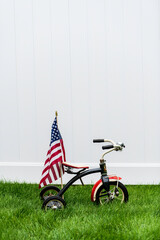 vintage tricycle with American flag on green grass with vertical white background and room for copy