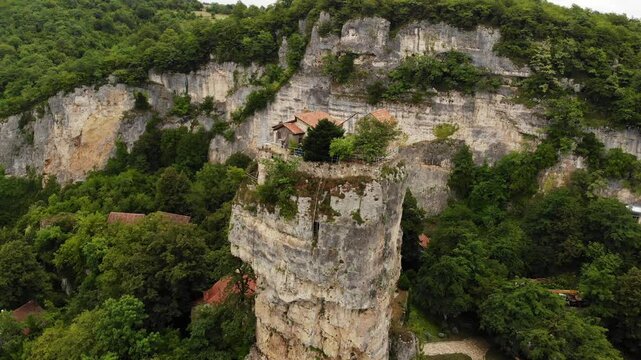 Drone aerial of Katskhi Pillar limestone monolith with Orthodox monastery on top in Chiatura, Georgia. Unique spiritual site of ascetic hermit monks, dramatic cliff in lush green landscape