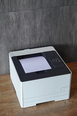 top view laser printer resting on a wooden floor, grey tile wall background, decor, technology, fashion, business, copy space