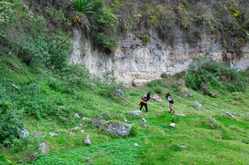 Two tourists helping each other exploring nature near a cliff