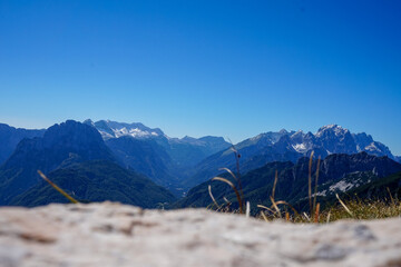 Breathtaking panoramic view of the Julian Alps with snow-capped peaks under a clear blue sky in...