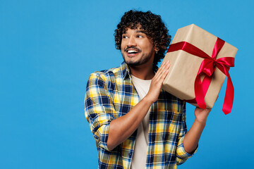 Young happy smiling Indian man he wear yellow checkered shirt casual clothes hold present box with...