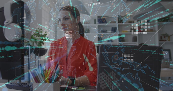 Analyzing global data woman wearing red blouse working at tech office desk, with holographic map