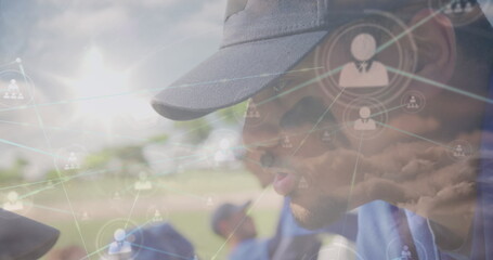 Leaning coach guiding kneeling team wearing blue jerseys on field with network overlays, copy space