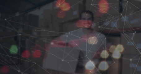 Holding box worker restocking shelves in warehouse, with digital network overlay and bokeh lights