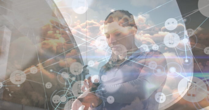 Checking athletic woman tapping smartwatch on rooftop, with cloud network icons on circular element