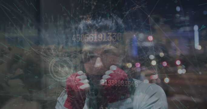 Holding fists boxer wearing hoodie and red wraps in night city skyline, with digital overlay - Powered by Adobe