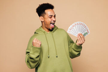 Young man of African American ethnicity wear green hoodie casual clothes hold fan of cash money in...