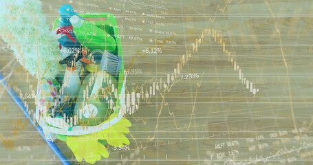 Displaying frog-shaped plush backpack resting on wooden floor with stock charts overlay, copy space