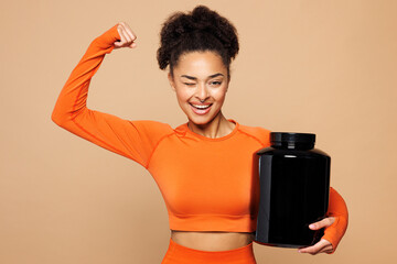Young fitness trainer instructor sporty woman sportsman wear orange clothes spend time in home gym hold sports nutrition supplement isolated on plain beige background. Workout sport fit abs concept.