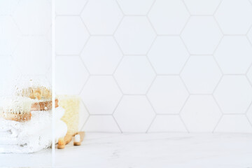 Marble table in bathroom with glass shower door with water droplets, towels, toothbrushes, sponges and body care comb in white. Minimal abstract background for product presentation. Design element.