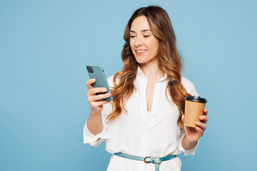 Young happy employee business woman corporate lawyer in shirt classic formal clothes work in office hold in hand use mobile cell phone drink coffee isolated on pastel blue background studio portrait