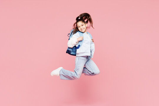 Full body young overjoyed excited fun cool school girl 8-9 years old wear blue casual clothes backpack hold books isolated on plain pink background children portrait. Childhood kids education concept. - Powered by Adobe