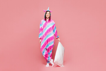 Full body young happy woman wear domestic costume hoody hold pillow behind head close eyes lying in...
