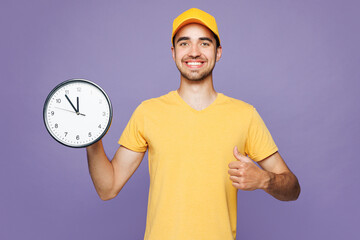 Young smiling happy delivery guy employee man wears yellow cap t-shirt uniform workwear work as...