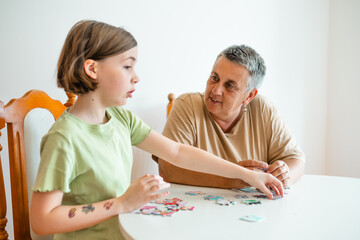 Grandmother and granddaughter doing puzzle at home.