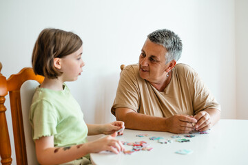 Grandmother and granddaughter doing puzzle at home.