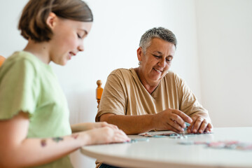 Grandmother and granddaughter doing puzzle at home.