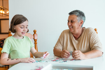 Grandmother and granddaughter doing puzzle at home.