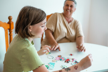 Grandmother and granddaughter doing puzzle at home.