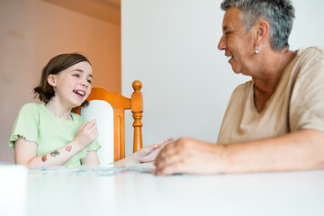 Grandmother and granddaughter doing puzzle at home.