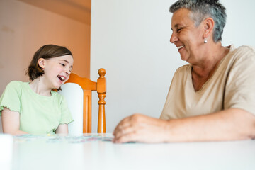 Grandmother and granddaughter doing puzzle at home.