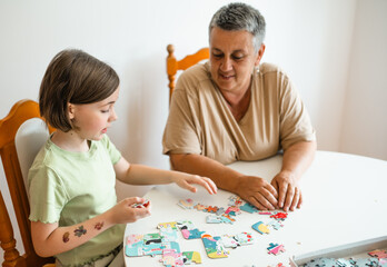 Grandmother and granddaughter doing puzzle at home.