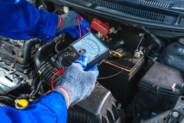 Close up mechanic using battery testing machine check up car battery in repair shop