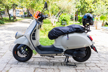 Modern gray scooter parked on cobblestone path. Urban commuting, minimalist lifestyle, and...
