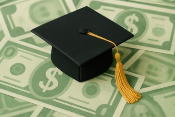 Graduation Cap Placed on a Background of Dollar Bills Representing the Cost of Education and Student Debt Challenges