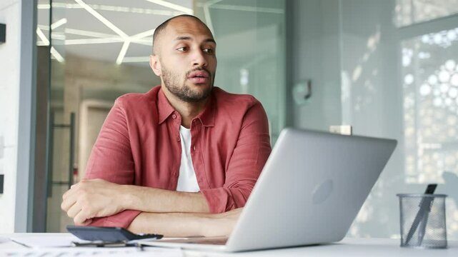 Overworked businessman is bored while sitting at desk at workplace in business office. Sleepy exhausted male employee is tired from working with laptop. A lazy worker procrastinates, gets distracted
